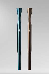 The metallic blue-green Olympic torch and metallic bronze Paralympic torch for Milan-Cortina 2026. The torches look like minimalist tubes that flare out slightly at the top.