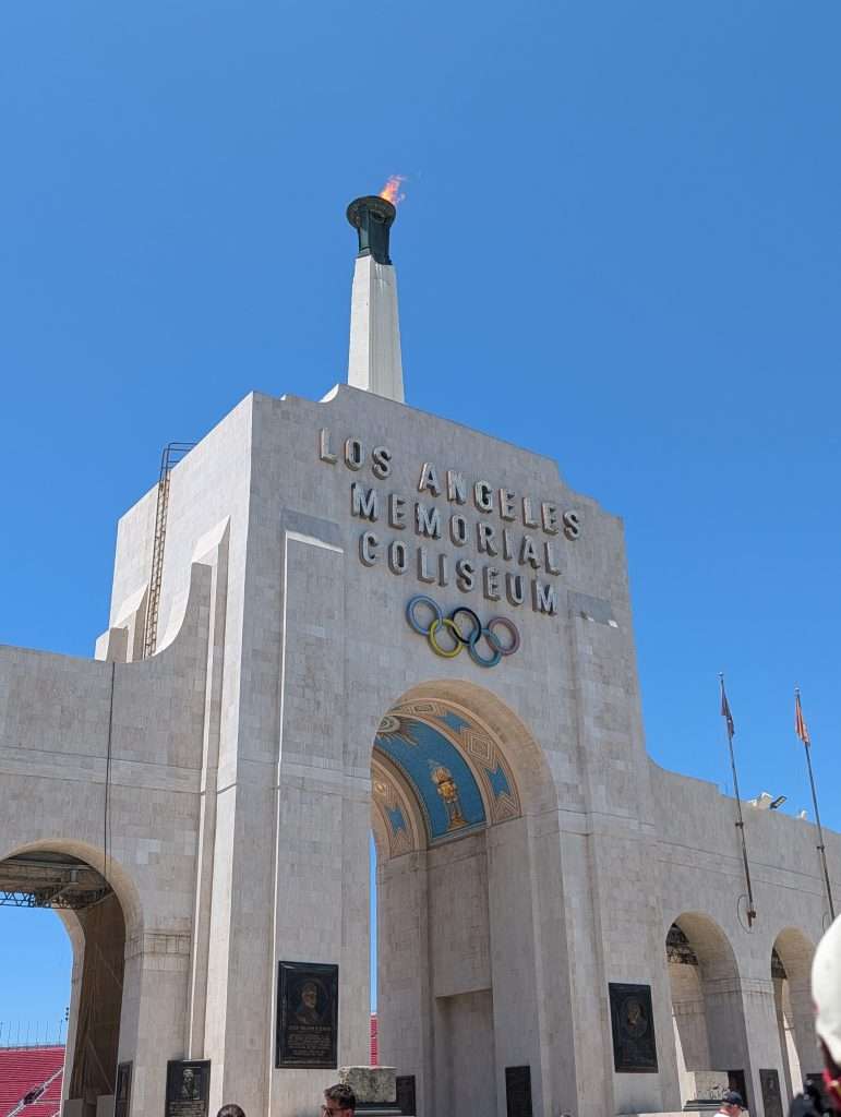 Entrance to the LA Coliseum with Olympic Rings and lit cauldron.